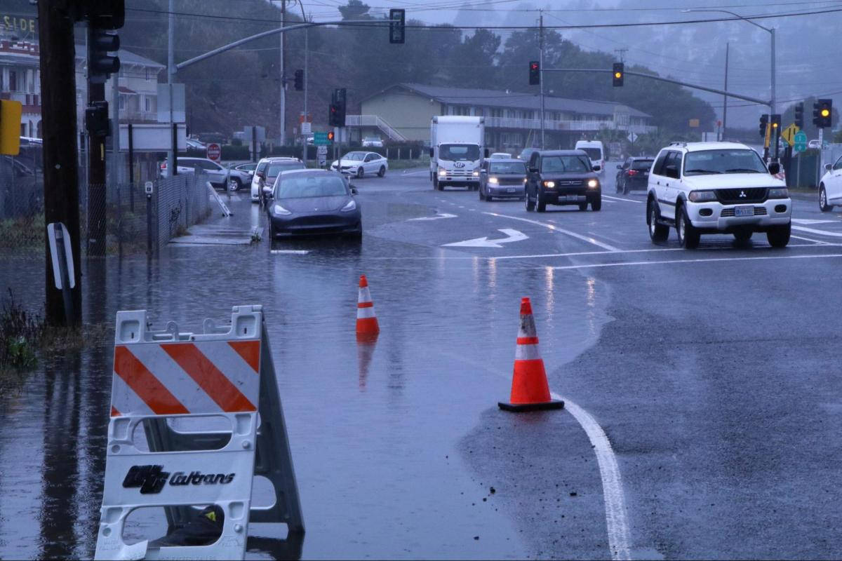A flooded intersection with cones and traffic barriers blocking traffic