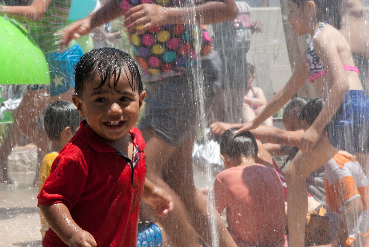 Children smiling and playing in sprinkler at Washington Elementary Natural Park